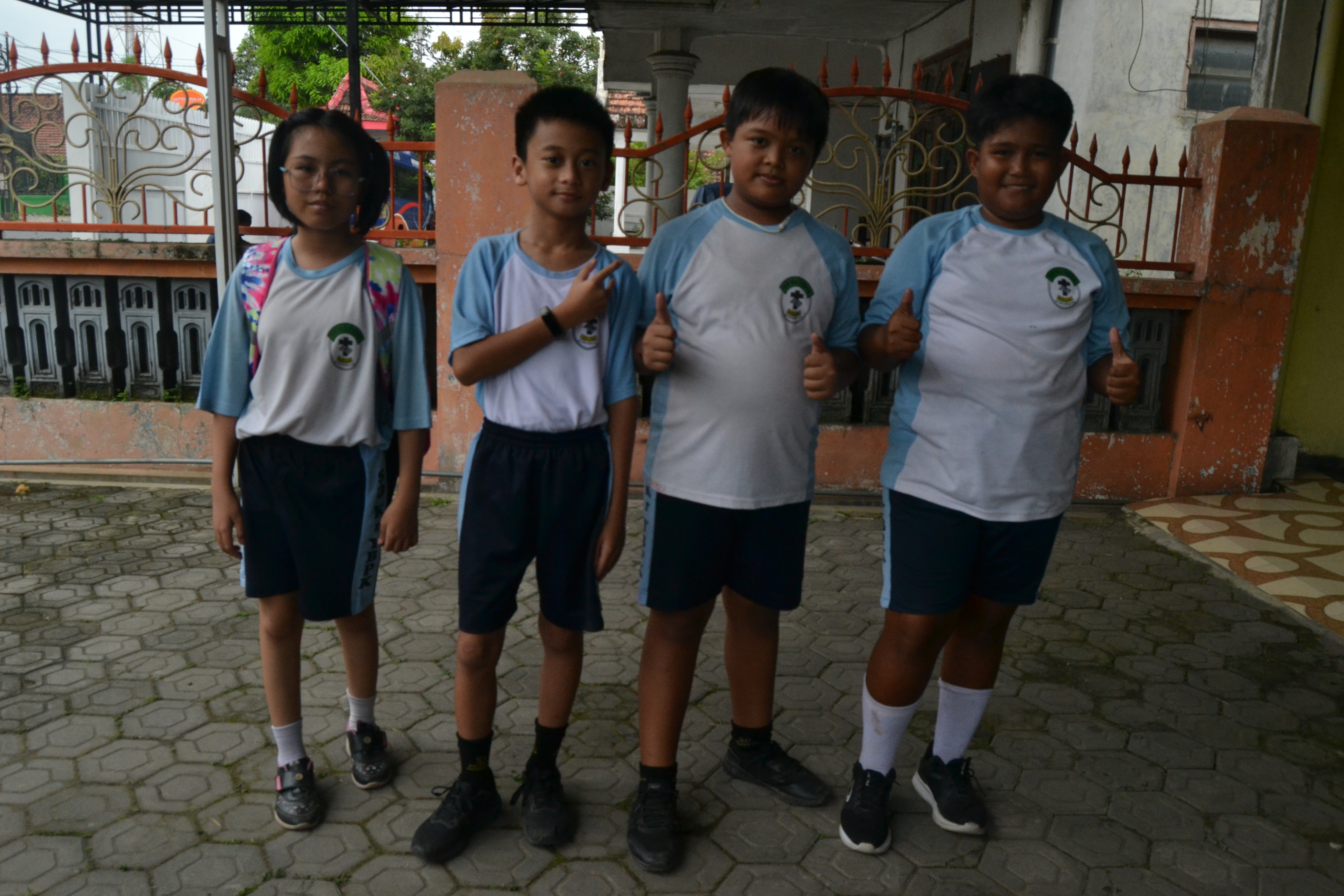 Empat murid berseragam olahraga berfoto bersama di teras
